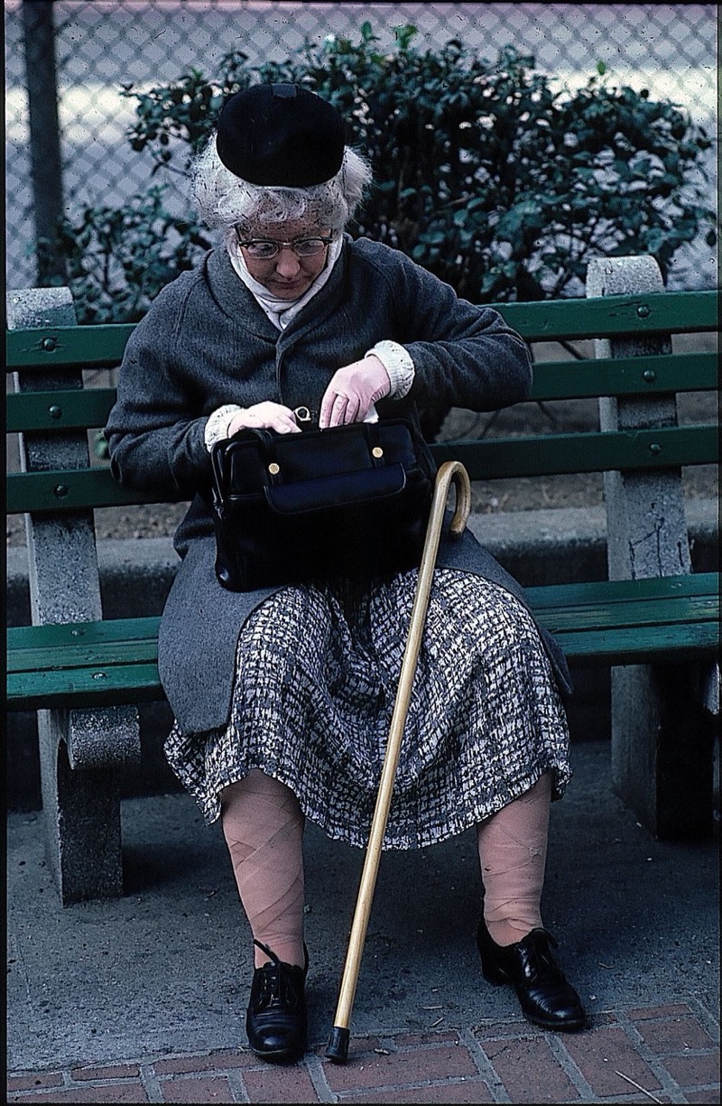 Patricia Moore in her aging disguise, sitting on a park bench with a cane and handbag